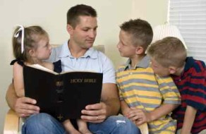 A father reads to his children from the Bible.